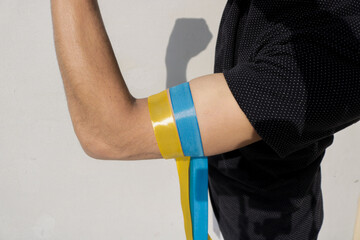 Solidarity with Ukraine. Ukraine flag colored ribbon tied on arm.