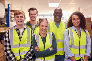 Portrait Of Multi-Cultural Team Wearing Hi-Vis Safety Clothing Working In Modern Warehouse
