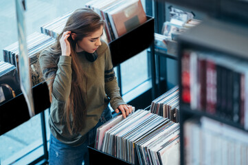 Woman choosing vinyl record in music record shop