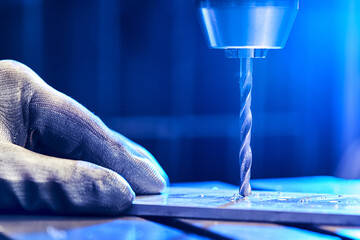 Employee drilling aluminium flat steel plate with bench drill. Metal Drill bit makes holes in Steel...