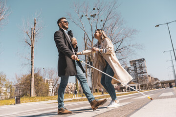 A blind male person using a white cane and walks with his female friend.They walk down the...