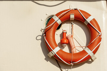 Close-up of an orange life buoy with an emergency light for localization on a boat deck with copy...