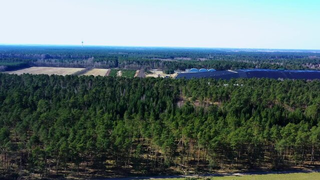 Aerial view of flat landscape in northern Germany with a pine forest, covered landfill and arable land