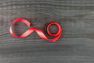 Red satin ribbon on a wooden dark table.