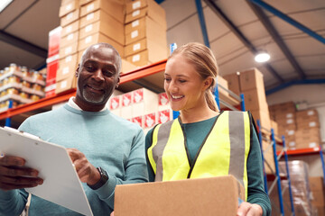 Male Team Leader With Clipboard In Warehouse Training Intern Standing By Shelves
