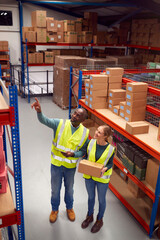 Male Team Leader With Digital Tablet In Warehouse Training Intern Standing By Shelves
