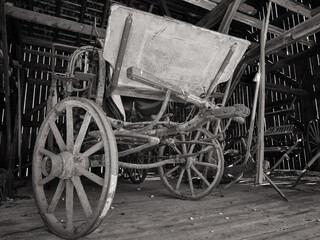 Fototapeta na wymiar Old style riding buggy with wooden and iron wheels stored in an old barn