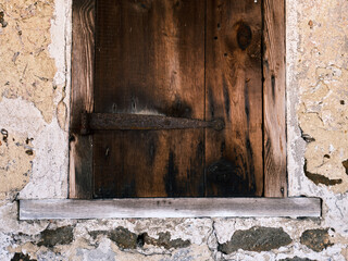 Wood planks form a homemade wooden shutter on an abandoned building
