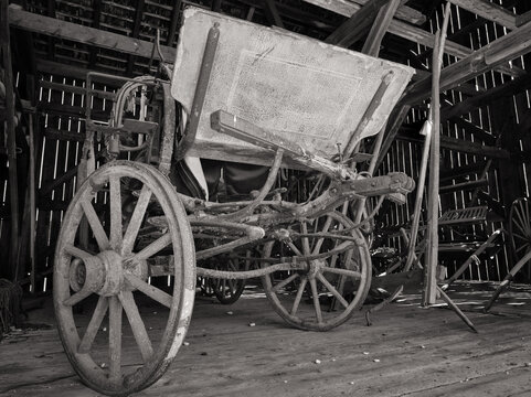 Old style riding buggy with wooden and iron wheels stored in an old barn