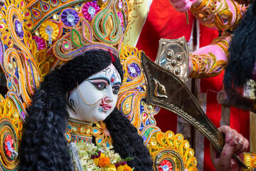 Face of Goddess Durga idol at decorated Durga Puja pandal, shot at colored light, at Kolkata, West...