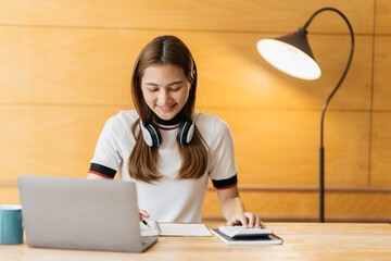 young attractive asian female employee wear earphone listen to digital online course development...