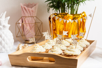 Tasty cupcakes with cream on wooden tray on holiday table with flags