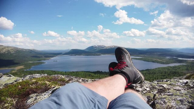 Hiker in shorts and hiking boots are enjoying the view over landscape scenery lake and mountains during summer. 4k videoclip.