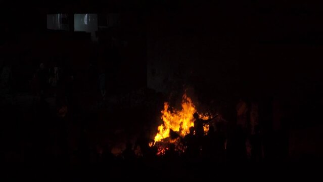 Slow motion shot of large bonfire during the Holi or Holika Dahan festival in India. Silhouette of people visible watching the bonfire at lohri festival. People enjoying lohri in India.	