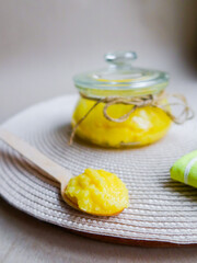 Pure ghee clarified butter in a glass jar on wooden spoon on beige background 