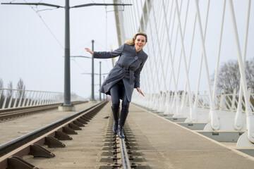 Woman crossing a rail bridge balancing on the tracks