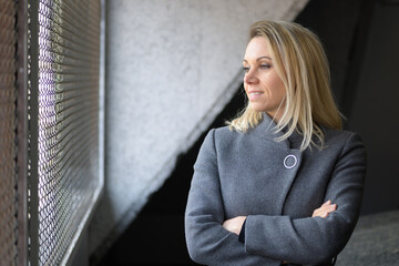 Woman standing in a stairwell staring out of a window