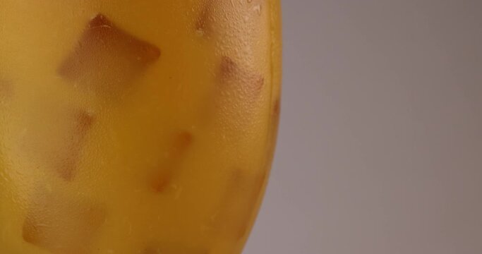 closeup rotating glass fill with orange juice flowing ice cube frost on the glass