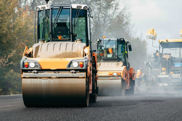 Vibratory asphalt rollers compactor compacting new asphalt pavement. Road service build a new...