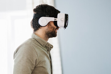 Serious ethnic man wearing VR goggles and looking away