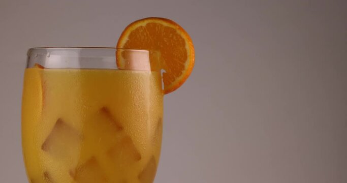 putting a slice of orange on rim of glass fill with orange juice ice cube frost on the glass