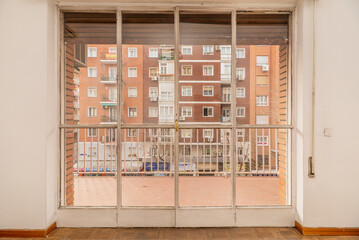 Iron and glass doors leading to a terrace with terrazzo floors and views of the street