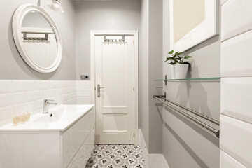 Toilet with white porcelain sink on wooden cabinet, stainless steel towel rail and glass shelf