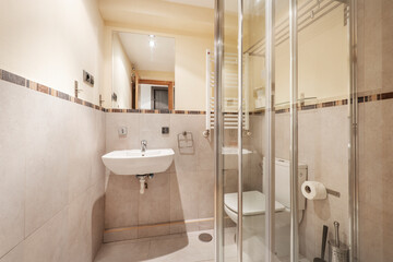Bathroom with white porcelain hanging sink, square frameless mirror and shower stall with chrome accents