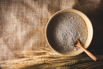 vista superior de un cuenco con harina de trigo integral, con espigas de trigo, sobre una tela de...