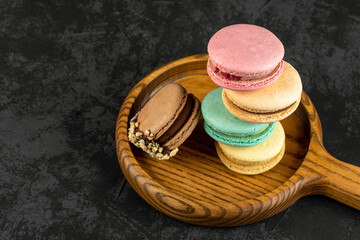 Macaroons stacked on a dark background. Delicious French cuisine dessert creatively decorated