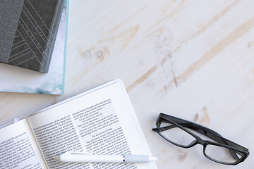 open bible, reading glasses and journal and pen on a white wood desk with copy space