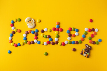 Easter inscription from colorful candies. Top view. Festive background. Food lettering.