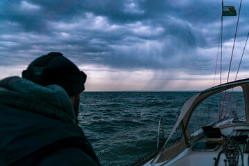 Closeup shot of a man riding a white boat on a cloudy day - Powered by Adobe