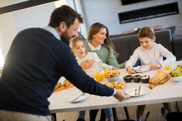 Young happy family talking while having breakfast at dining table