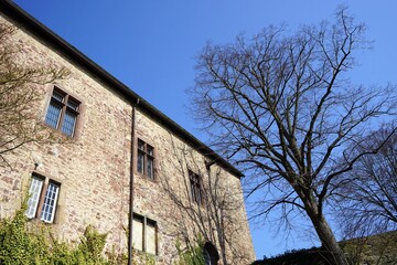 Altes Mauerwerk aus Bruchstein und Naturstein der Burg vor blauem Himmel bei Sonnenschein an der...