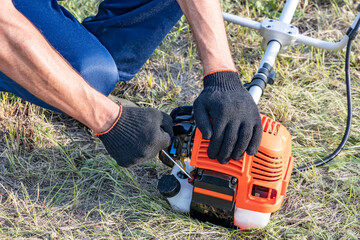 Professional start motor of plant petrol lawnmower. Man pulls on a winding cable starts the engine...