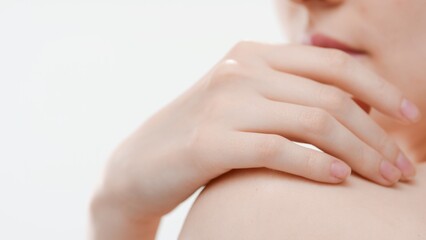 Big close-up shot of female hand lays on shoulder against white background | Skin brightening concept