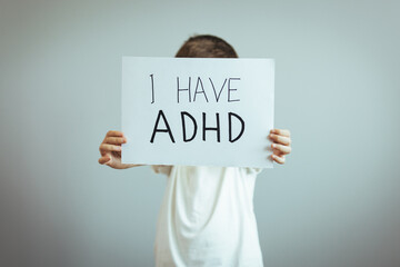 Young boy holds ADHD text written on sheet of paper. ADHD is Attention deficit hyperactivity disorder. Close up. Attention Deficit Hyperactivity Disorder or ADHD