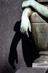 A hand on an urn casts its shadow on the wall behind.