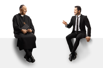 Professional man in suit and tie talking to a priest seated on a blank panel