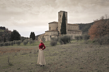 young woman in front of the abbey of sant'antimo, tuscany, italy