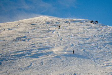 Lone skier on the snow-covered hill under the sunny sky