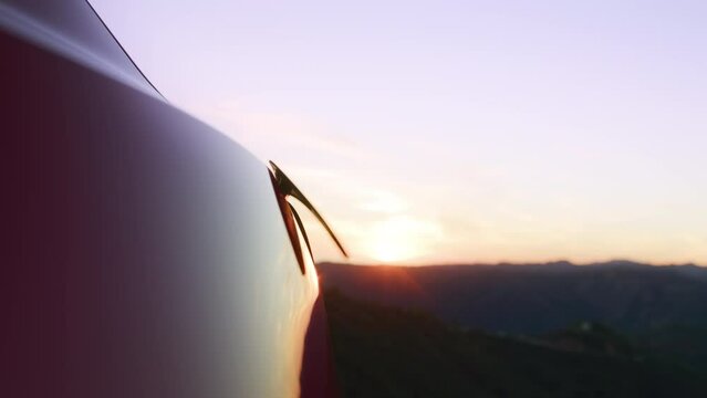 Slow motion unrecognizable man unplugging zero emission electric car on sunset