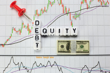 Debt-Equity written on white cube with candlestick chart background. Conceptual image for D/E ratio.
