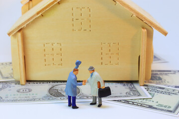 Two business men are making commitment to mortgage on dollar and house background.