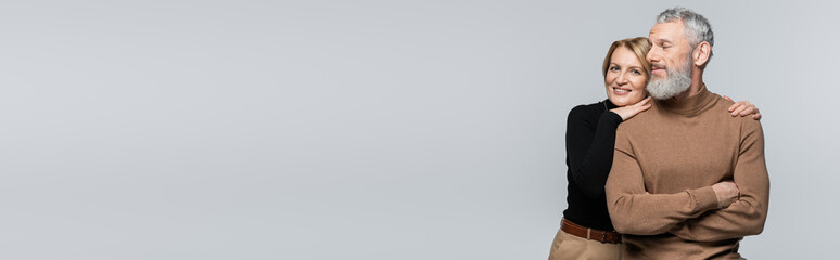 Middle aged woman hugging bearded husband isolated on grey, banner.