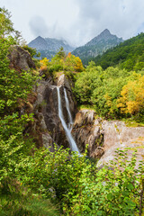 Idyllic landscape in the Italian Alps with a waterfall, forests and Autumn colors and mountain in...