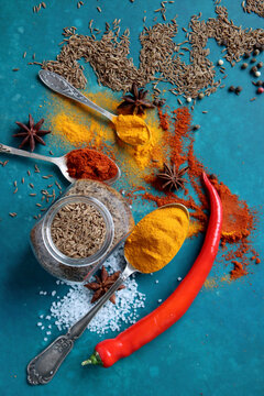 Colorful image of aromatic spices on vibrant blue background. Turmeric, paprika, pepper, anise, salt, garlic, cinnamon close up photo. 