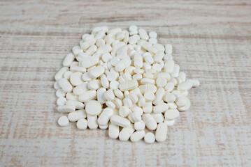 pile of pills on a wooden background.