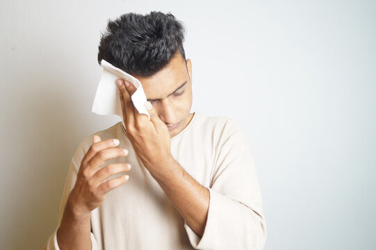 Young man wiping the sweat off his forehead with a napkin